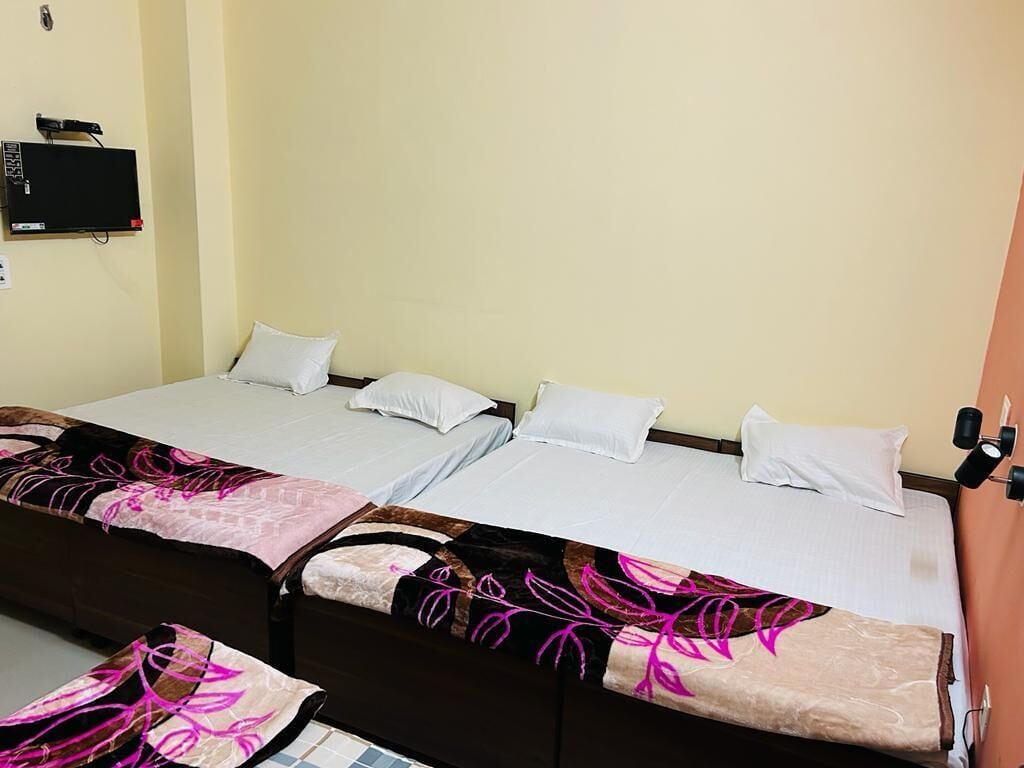 A double bed with a floral bedspread, a bedside table, and a wall-mounted TV.