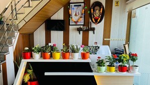 A reception desk with potted plants, a framed picture, and a staircase. - Cohouse (Bawal)