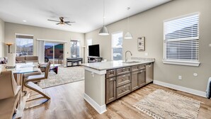 A modern kitchen with a central island, built-in appliances, and a dining area with a sofa and table.