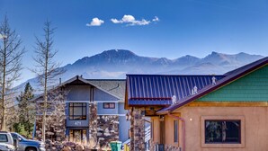 A mountain cabin with a stone facade, a number '471' on the side, and a view of distant mountains.