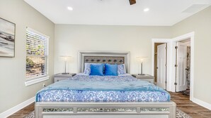A bedroom with a bed, two bedside tables, a ceiling fan, and a window with blinds.