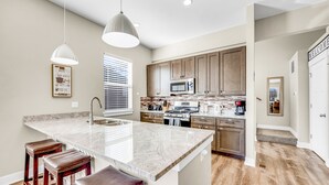 A modern kitchen with a large island, stainless steel appliances, and wooden cabinets.