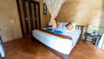 Un dormitorio con cama, mesita de noche, cortinas en la ventana y aire acondicionado instalado en la pared.