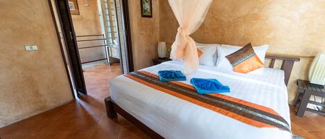 A bedroom with a bed, a nightstand, a chair, and a door leading to a balcony.