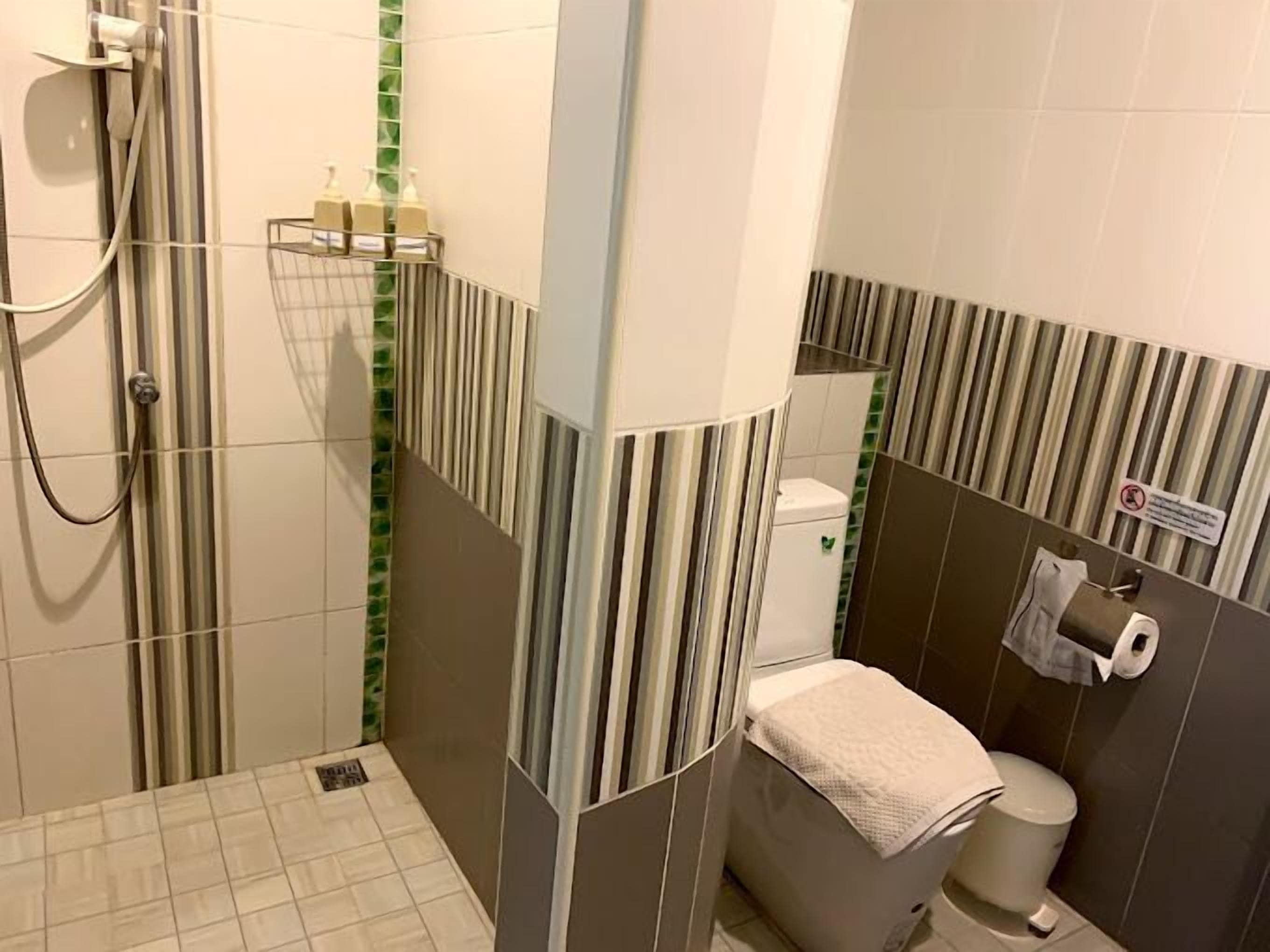 A bathroom with a shower, toilet, and a towel rack.