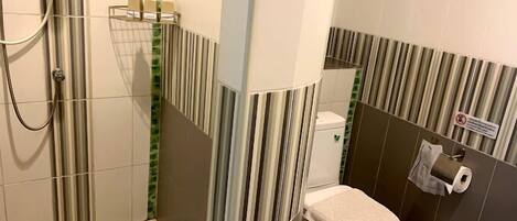 A bathroom with a shower, toilet, and a towel rack.