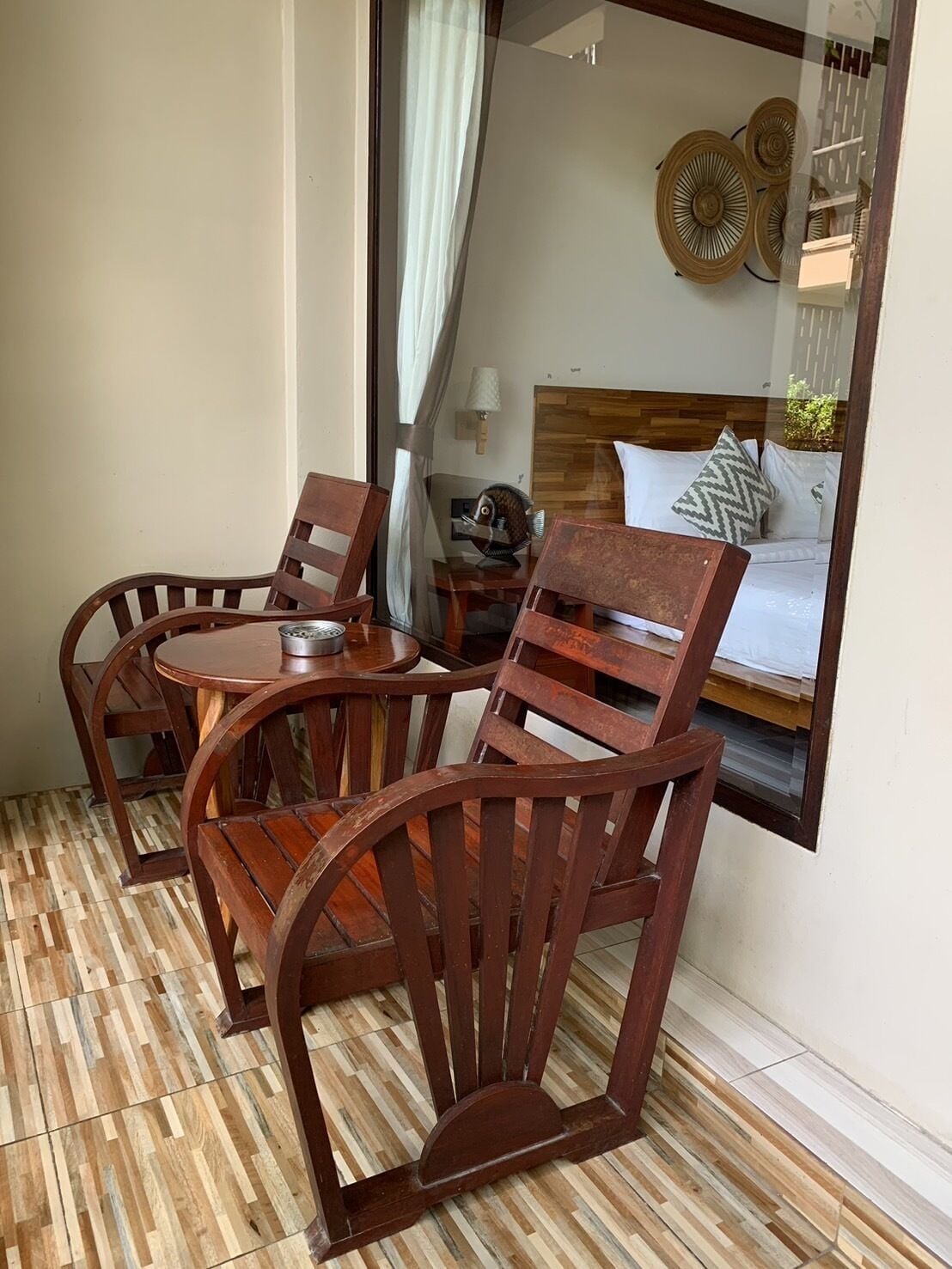 Un ensemble de salle à manger en bois comprenant une table ronde et quatre chaises, une petite table avec une lampe, et un lit avec des oreillers et une tête de lit en arrière-plan.