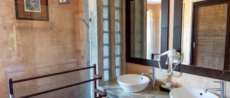 Un baño moderno con dos lavabos, un espejo grande y una cabina de ducha con paredes de vidrio.