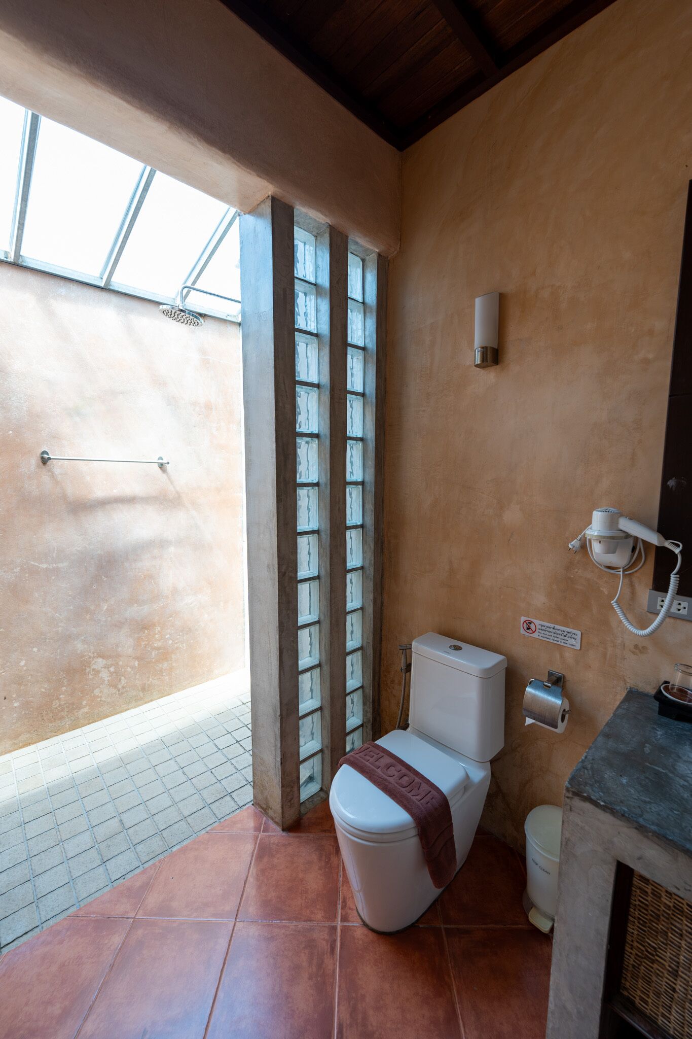 Une salle de bain comprenant des toilettes, un espace douche et une porte en verre donnant sur un balcon.