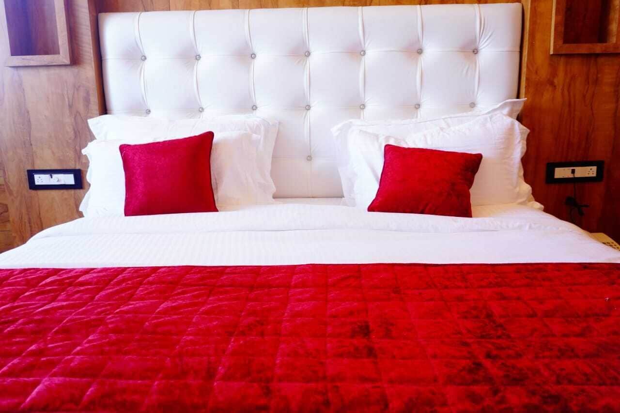 A bed with a tufted headboard, white bedding, and red pillows.