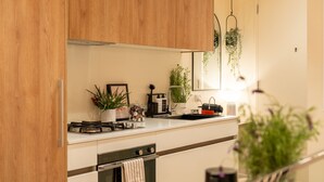 Una cocina moderna con armarios de madera, encimera blanca y diversos electrodomésticos.