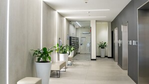 Un pasillo moderno con plantas en macetas, zonas de estar y un diseño limpio y minimalista.