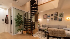 Una sala de estar moderna con una escalera espiral, un sofá, una mesa de centro y una alfombra.