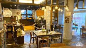 A cozy cafe with wooden furniture, hanging light bulbs, and a visible clock on the wall. - KULABO TAISHOKAN (Nagato)