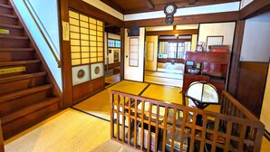 A traditional Japanese room with tatami flooring, a wooden staircase, and a shoji screen door. - KULABO TAISHOKAN (Nagato)