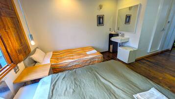 Ett hotellrum med två sängar, en trädörr, ett litet handfat och en spegel.