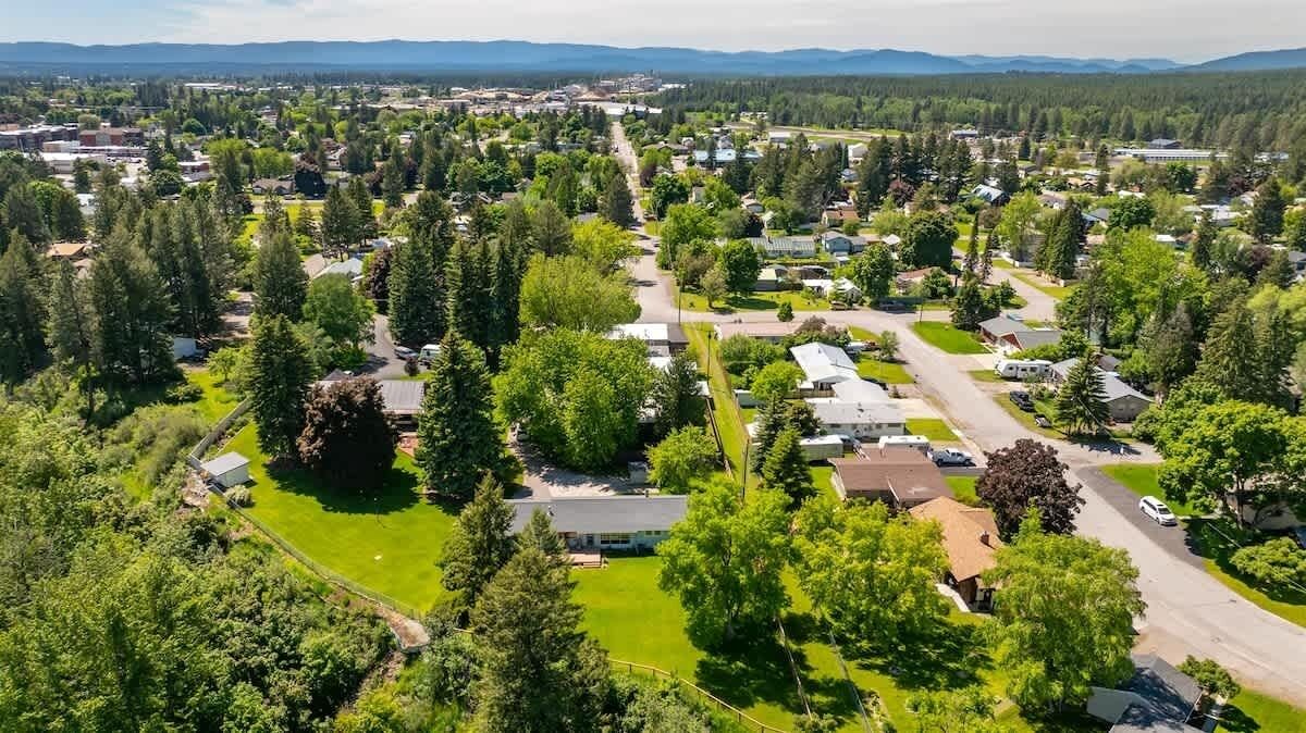 An aerial view of a residential area with houses, green spaces, and a clear sky.
