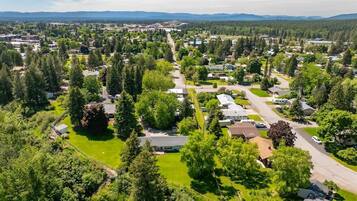 An aerial view of a residential area with houses, green spaces, and a clear sky.