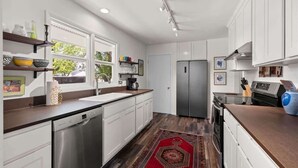 Una cocina moderna con armarios blancos, un refrigerador de acero inoxidable y un lavavajillas.