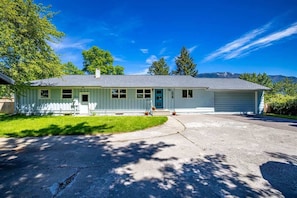 A single-story house with a front porch, a garage, and a driveway. - Scenic Bluebird House with Mountain views, AC & Ho (Columbia Falls)