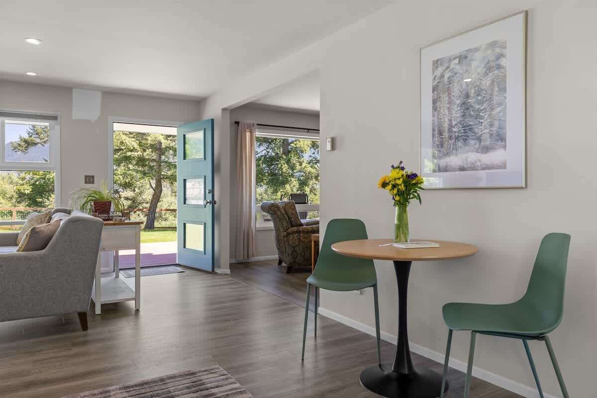 A modern living room with a sofa, chairs, a round table, and a vase of flowers.