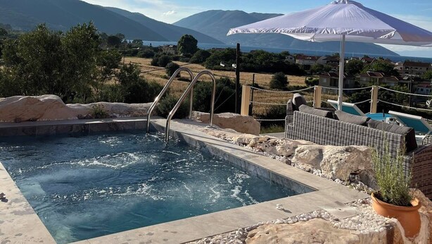 Un espace piscine avec vue sur les montagnes et un grand parasol.