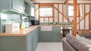 A kitchen with wooden beams, a sink, a stove, and a window. - Twosome (Halesworth)