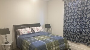 A bedroom with a bed, two bedside tables, a lamp, a patterned curtain, and a carpet. - New amazing location  (Antioch)