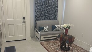 A living room with a sofa, a patterned curtain, a small table with a vase, and a rug. - New amazing location  (Antioch)