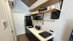 A compact kitchen with a refrigerator, microwave, coffee maker, and a small countertop.