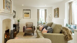 Ein gemütliches Wohnzimmer mit Kamin, einer Couch, einem Sessel und einem Couchtisch.