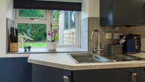 Eine moderne Küche mit großem Fenster, einer Spüle und einer Kaffeemaschine.