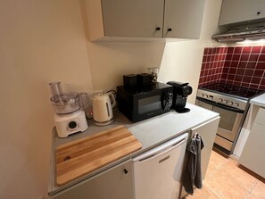Eine kleine Küche mit Mikrowelle, Toaster, Wasserkocher und kleinem Kühlschrank.