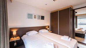 A hotel room with a large bed, two bedside tables with lamps, a wardrobe, and a framed picture on the wall.