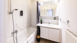 A modern bathroom with a bathtub, a shower, a sink, and a mirror.