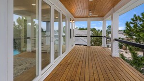 A wooden deck with glass doors leading to a pool area. - FREE Golf Cart | New home located on resort style pool | Massive Kitchen/Private Balconies/Sleeps 12 (Santa Rosa Beach)