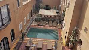 A courtyard with a swimming pool, outdoor seating, and a spiral staircase. - Kasbah La Cigogne (Aït Benhaddou)