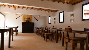 A dining area with wooden tables and chairs, a tiled floor, and a rustic ceiling. - Kasbah La Cigogne (Aït Benhaddou)