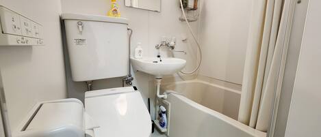Une salle de bain avec des toilettes, un lavabo et une douche.