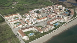 Luftaufnahme eines Küstenresorts mit mehreren Gebäuden, einem Strand und einem Poolbereich.