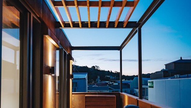 A wooden deck with a view of the cityscape, a table, and chairs. - 95 Hardy Street Apartment 4 (Nelson)
