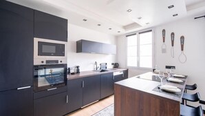 Uma cozinha moderna com armários escuros, micro-ondas embutido e uma ilha grande com banquetas.
