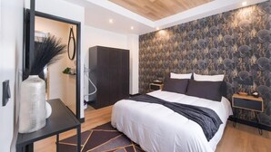 Quarto moderno com cama grande, espelho, guarda-roupa e papel de parede estampado.