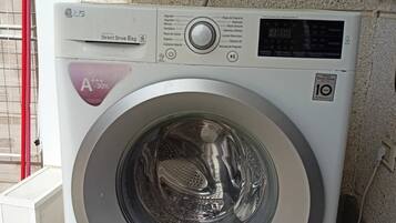 Una lavadora de carga frontal con pantalla digital, una manguera de entrada de agua y un panel de control con varias opciones.