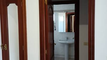 A hallway leading to a bathroom with a sink and mirror.