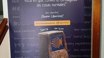 A sign with multilingual greetings and a hashtag for a walking route.