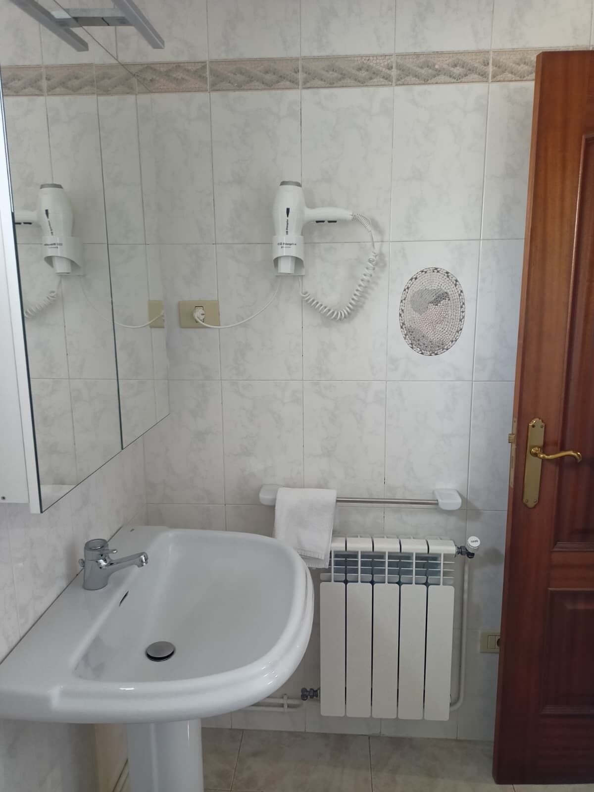 Une salle de bain équipée d’un lavabo, d’un miroir, d’un porte-serviettes et d’un radiateur.