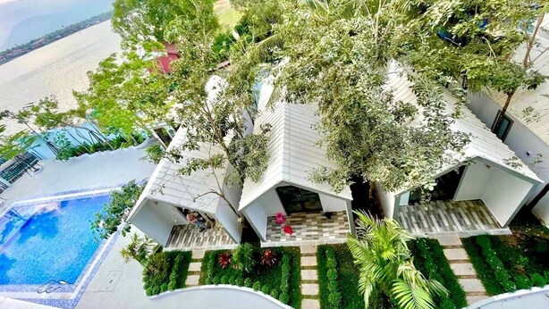 Une villa moderne dotée d’une piscine, entourée d’une végétation luxuriante et offrant une vue sur la mer.