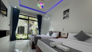 Une chambre d’hôtel moderne avec deux lits, une grande porte-fenêtre coulissante donnant sur un balcon et un plafond doté d’un éclairage LED bleu.