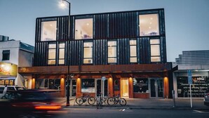 Ein modernes Gebäude mit großen Fenstern und einer Holzfassade, das einen ebenerdigen Eingang und einen sichtbaren Laden besitzt.